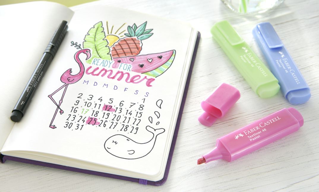 notebook with a sketch of a flamingo, fruits and a monthly overview next to three colorful textliner